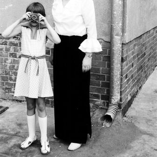 A woman teaching a young girl to use a camera.