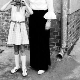 A woman teaching a young girl to use a camera.