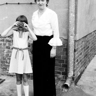 A woman teaching a young girl to use a camera.
