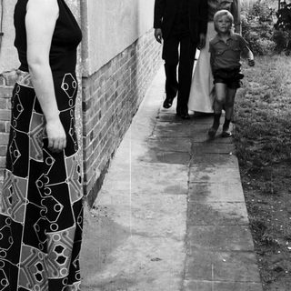 Family walking outside near a house. Woman observing.