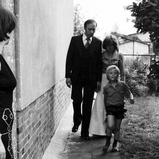 Family walking outside near a house. Woman observing.
