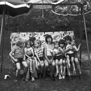 Group of children posing together outdoors under tent.