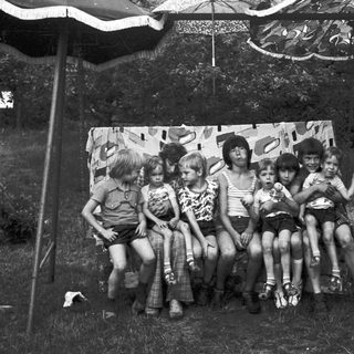 Group of children posing together outdoors under tent.
