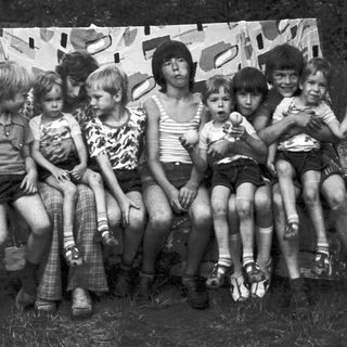 Group of children posing together outdoors under tent.