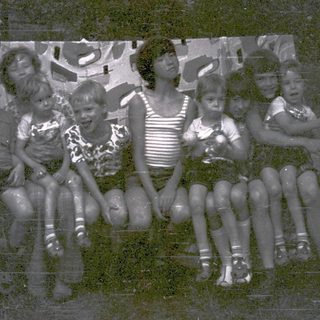 Group of children posing together outdoors in vintage clothing.