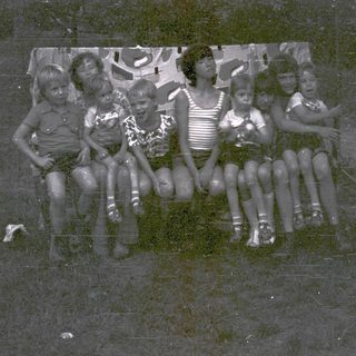 Group of children posing together outdoors in vintage clothing.