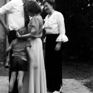 Family group hugging outdoors in vintage clothing.