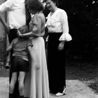 Family group hugging outdoors in vintage clothing.
