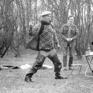 Four people camping in forest, preparing food.