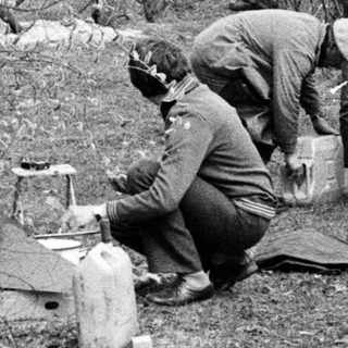 People camping outdoors setting up equipment.