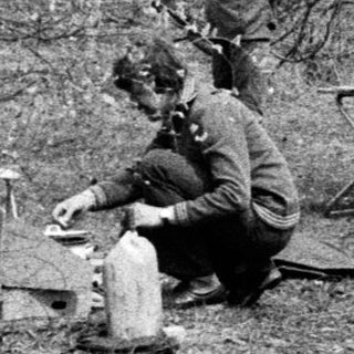 Soldiers taking cover and resting in a wooded trench.