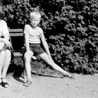 Family sitting on bench outdoors in park.
