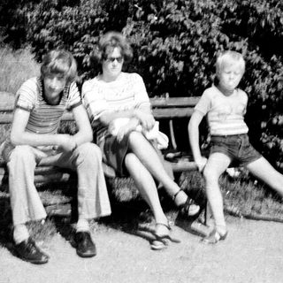 Three children sitting on a bench outdoors.