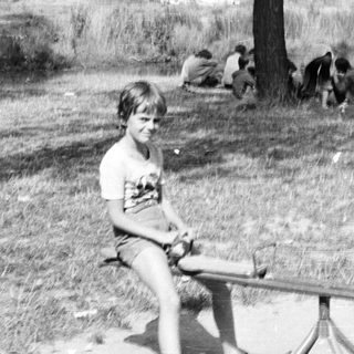 Children playing outdoors with swing and cows in background.