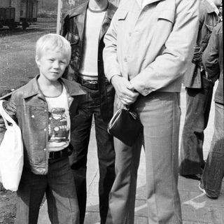Three men and a young boy posing outdoors near train tracks.