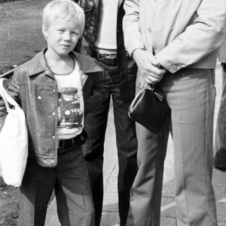 Three men and a young boy posing outdoors near train tracks.