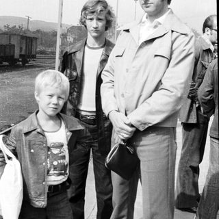 Three men and a young boy posing outdoors near train tracks.