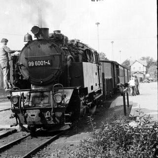 Steam locomotive numbered 99 6001-4 pulling passenger cars.