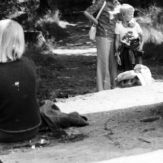 People gathering near a monument labeled "Frieden" in a park.