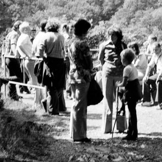 Group of people gathered around outdoor hot springs area.