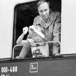 Man waving from old train carriage door.