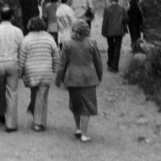 People walking through medieval stone gatehouse entrance.