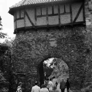 People walking through medieval stone gatehouse entrance.