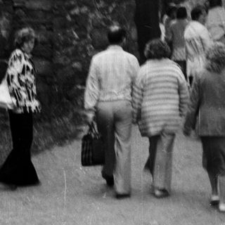 People walking through medieval stone gatehouse entrance.