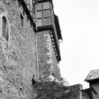 Medieval stone tower with two figures leaning on battlements.