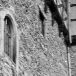 Medieval stone tower with two figures leaning on battlements.