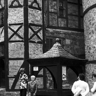 Timeless photo of people near Tudor-style half-timbered building.