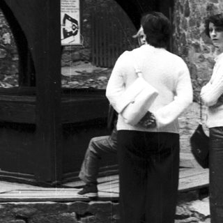 Timeless photo of people near Tudor-style half-timbered building.