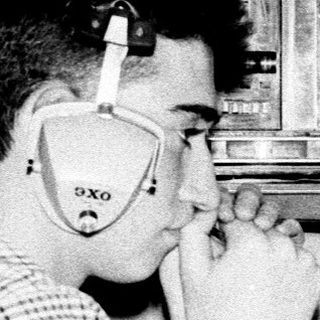 Man using vintage telephone in room with old electronics.
