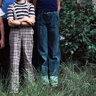 Five children and two adults posing near a vintage Volkswagen van.