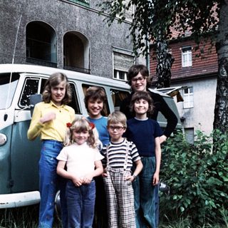 Family posing together outside vintage van.