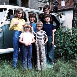 Family posing together outside vintage van.