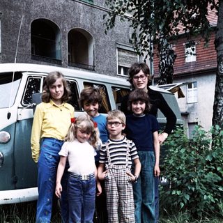 Family posing outdoors near vintage van.