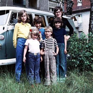 Family posing outdoors near vintage van.