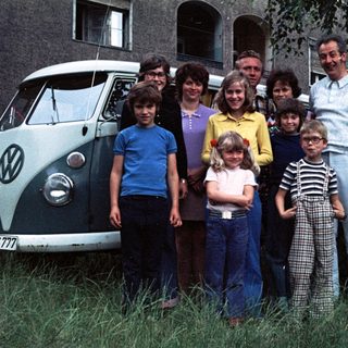 Family posing together outside a Volkswagen van.