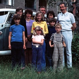 Family posing together outside a Volkswagen van.