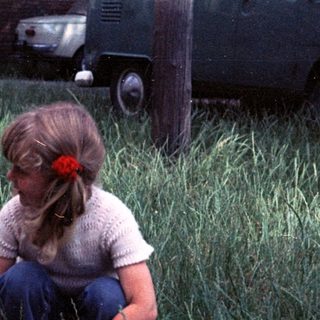 Two children playing in tall grass outdoors.