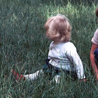 Two children playing in tall grass outdoors.