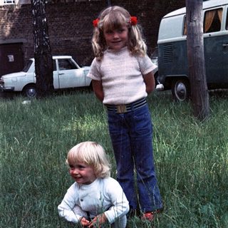 Two children playing in grassy backyard.