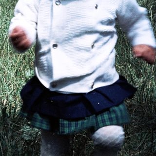 Joyful toddler running outdoors in grassy area.