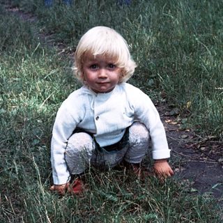 Young child playing outdoors in grassy yard.