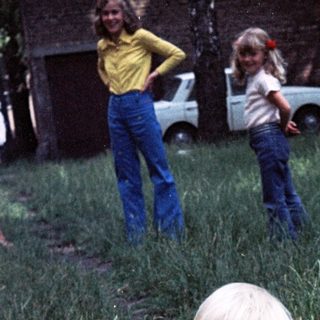 Young child playing outdoors in grassy yard.