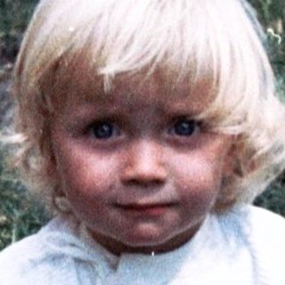 Young child playing outdoors in grassy yard.