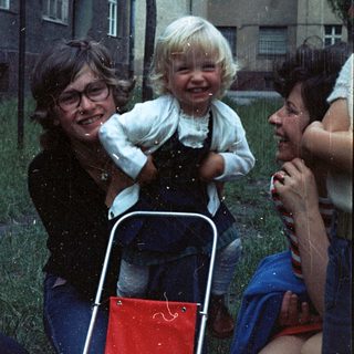 Happy family enjoying rain with child in stroller.
