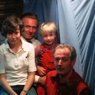 Family group photo in dimly lit indoor setting.