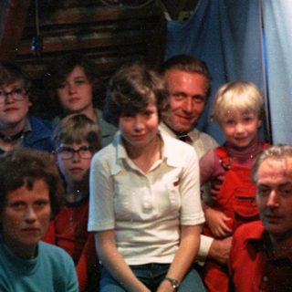 Family group photo in dimly lit indoor setting.
